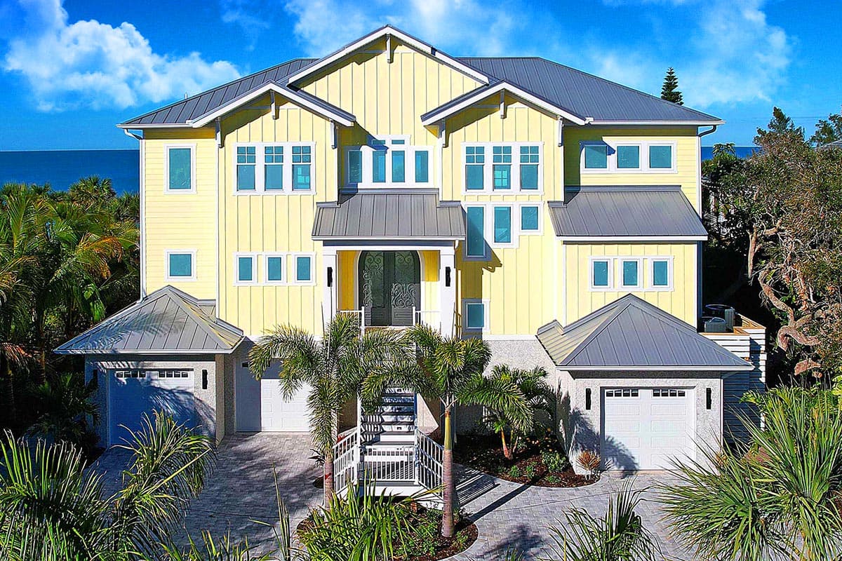 House plan exterior: Three-story Modern Coastal home with gabled roofs, twin garages, and a central covered entryway with stairs.