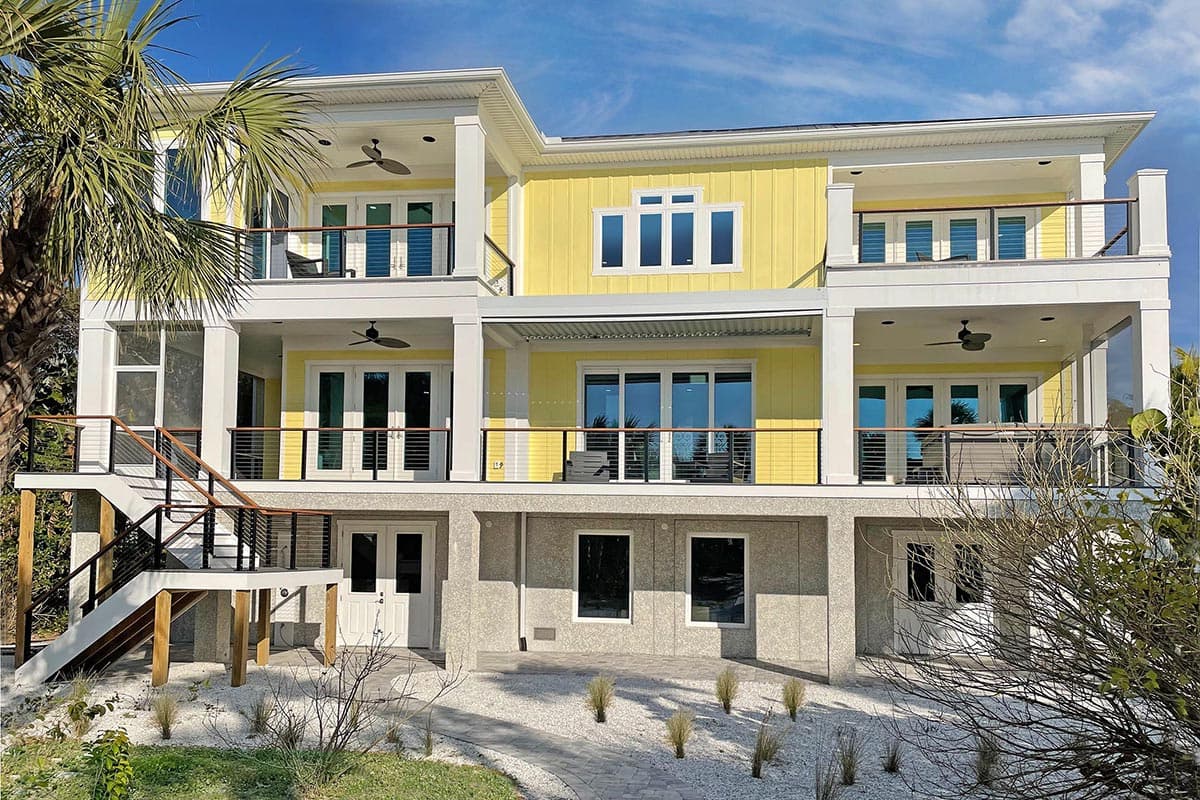Three-story Modern house plan exterior with balconies, large windows, and a raised foundation.