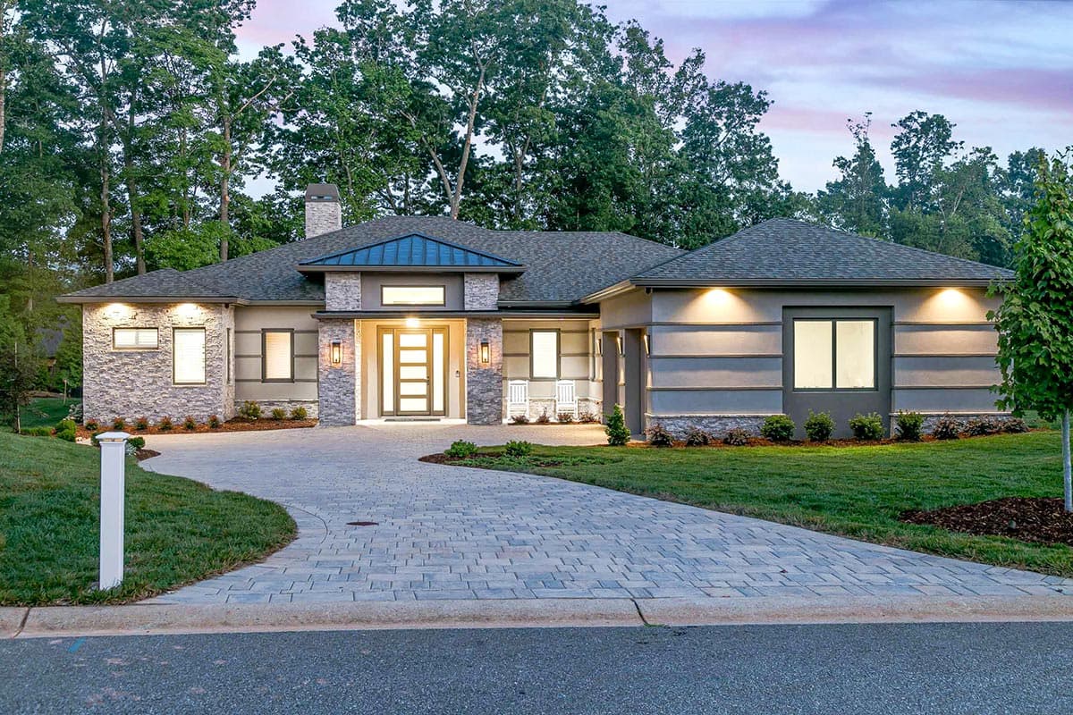 House plan exterior: Single-story home with a stucco and stone facade, multi-gabled roof, and prominent central entrance.