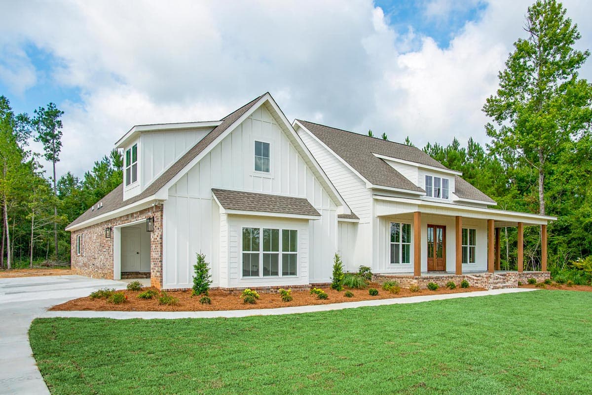 Modern Farmhouse house plan exterior with white board and batten siding, brick accents, wraparound porch, and side-entry garage.