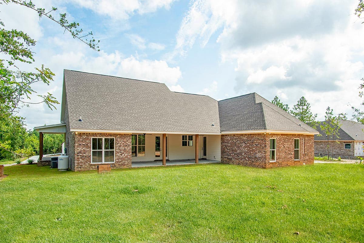 House plan exterior: brick one-story home with covered porch, multiple gables, and large windows.