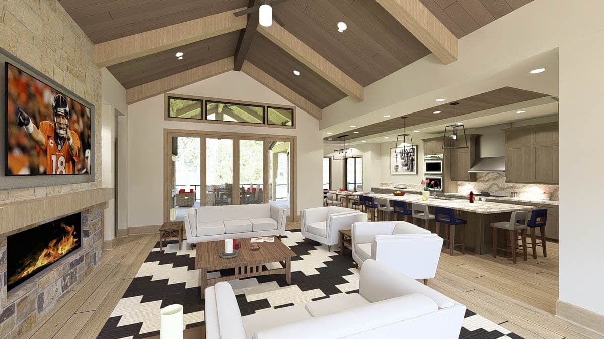 Open-concept living area with vaulted wood beam ceiling, stone fireplace, and adjacent kitchen with island.