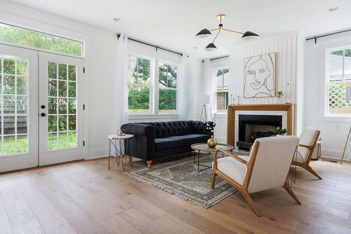 Living room with French doors, fireplace, tufted sofa, accent chairs, and hardwood floors.