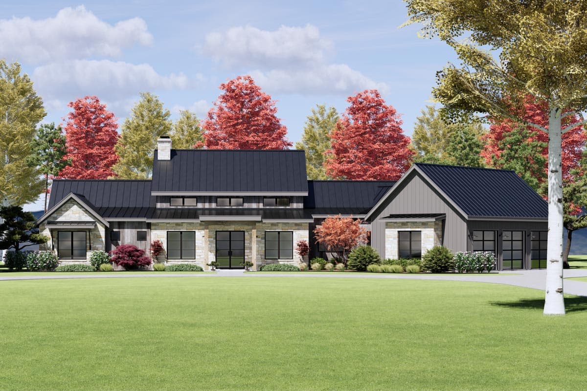 A modern, single-story home with a black metal roof, stone accents, and a large lawn. Red and gold trees provide a colorful backdrop.