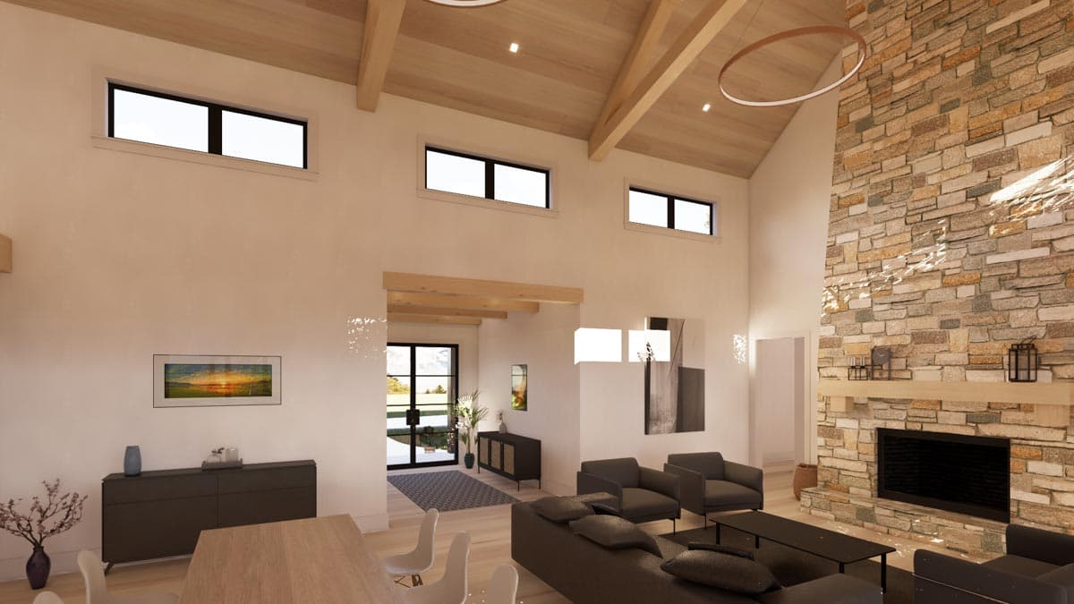 Spacious, modern living room with a stone fireplace, high ceilings with exposed beams, and large windows. Furnished with dark grey seating.