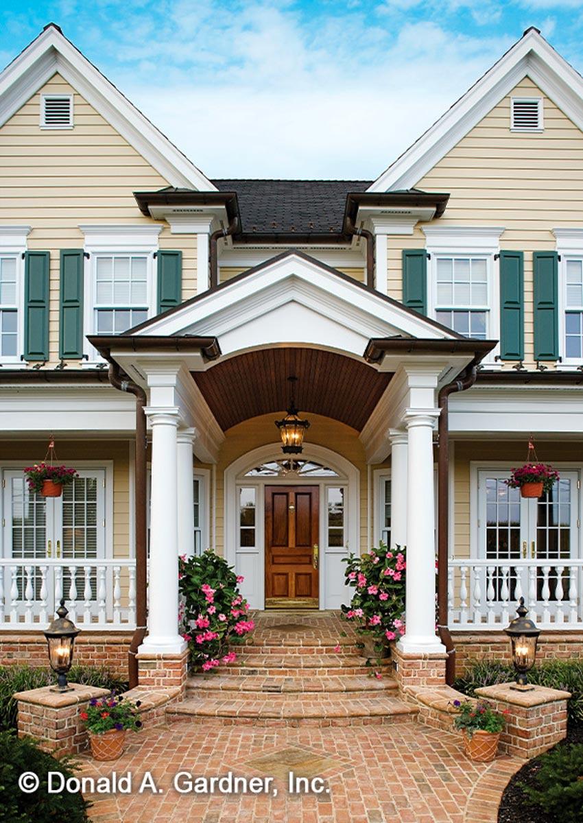 House plan exterior: Two-story home with gabled dormers, covered entryway with columns, double front doors, and white balustrade porches.