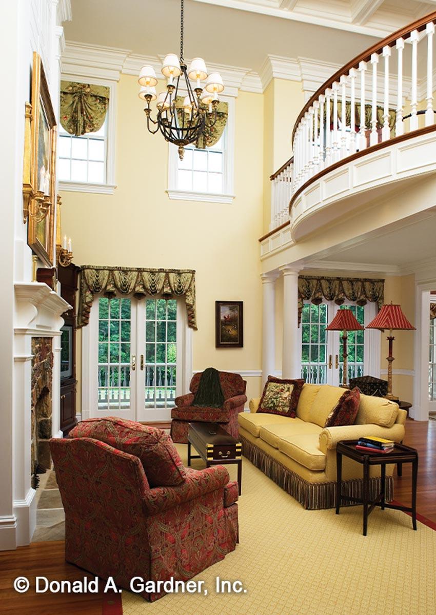 Great room with fireplace, double doors, two-story ceiling, and curved balcony overlooking the space.