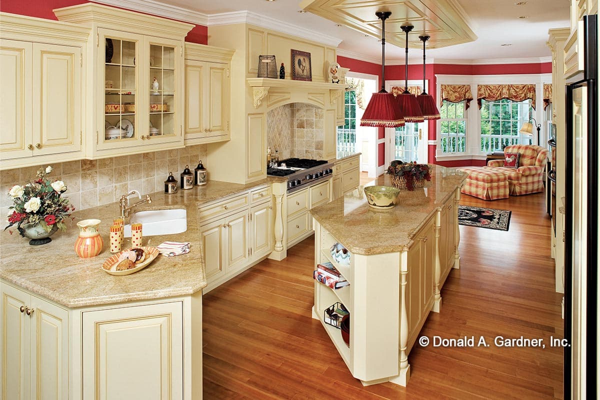 Interior view of a kitchen with a large island, range hood, pendant lights, and bay windows.