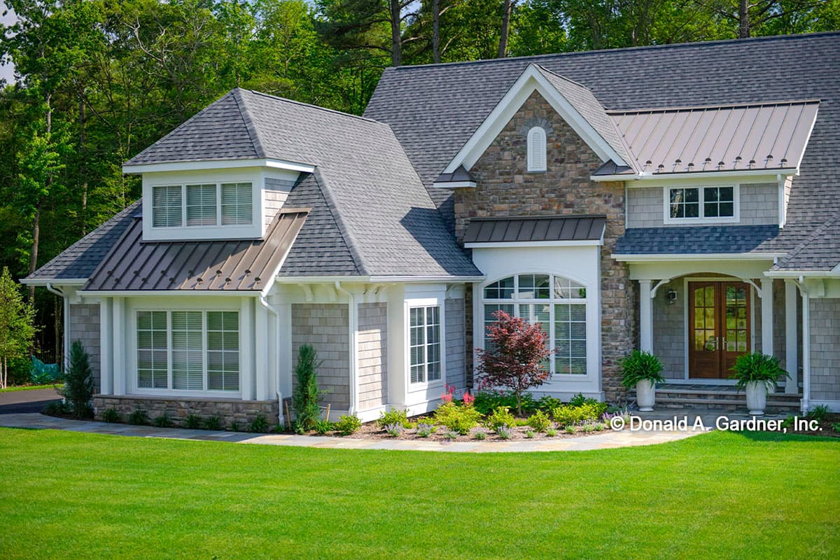 House plan exterior with stone accents, metal roof dormers, gables, and a covered front entry with double doors.