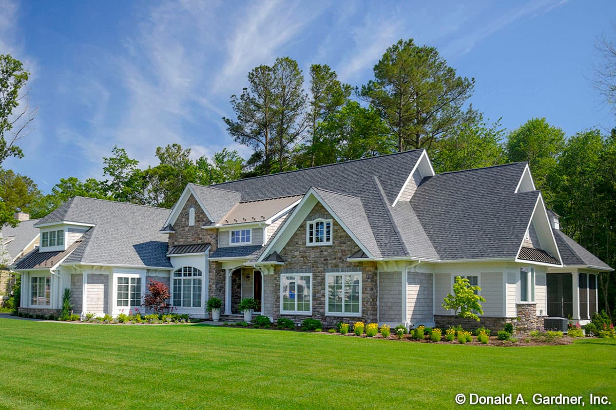 House plan exterior: Two-story home with stone and shingle siding, multiple gables, dormers, and a screened porch.