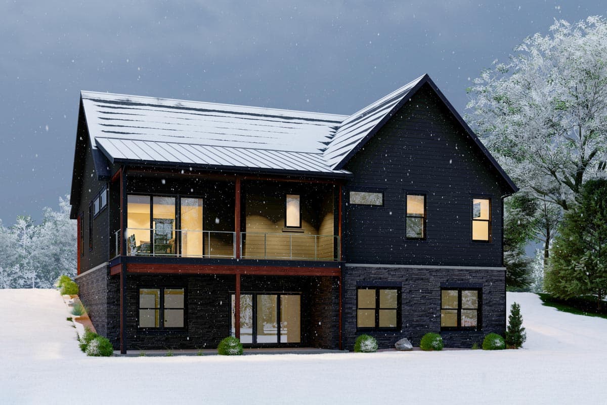 House plan exterior: Two-story modern home with dark siding, stone foundation, covered upper balcony, and metal roof in a snowy setting.
