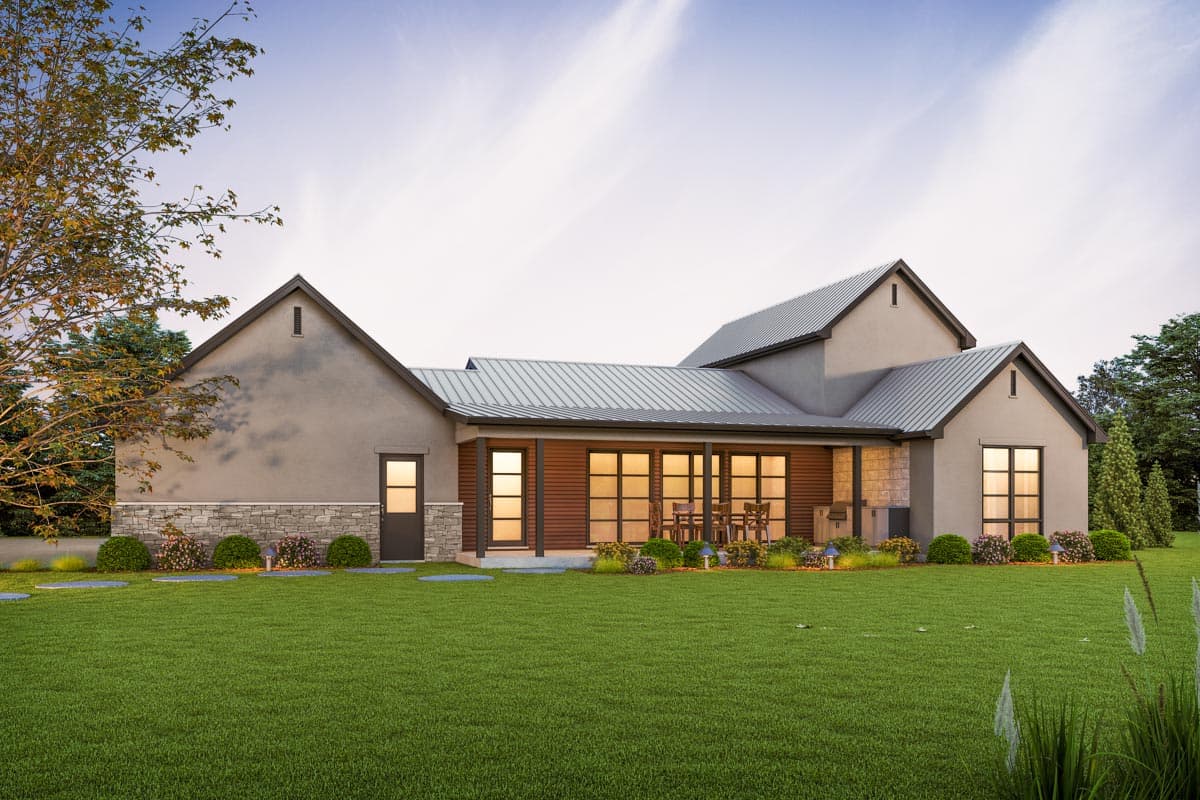 House plan exterior with metal roof, stone base, covered patio with outdoor dining, and large windows.