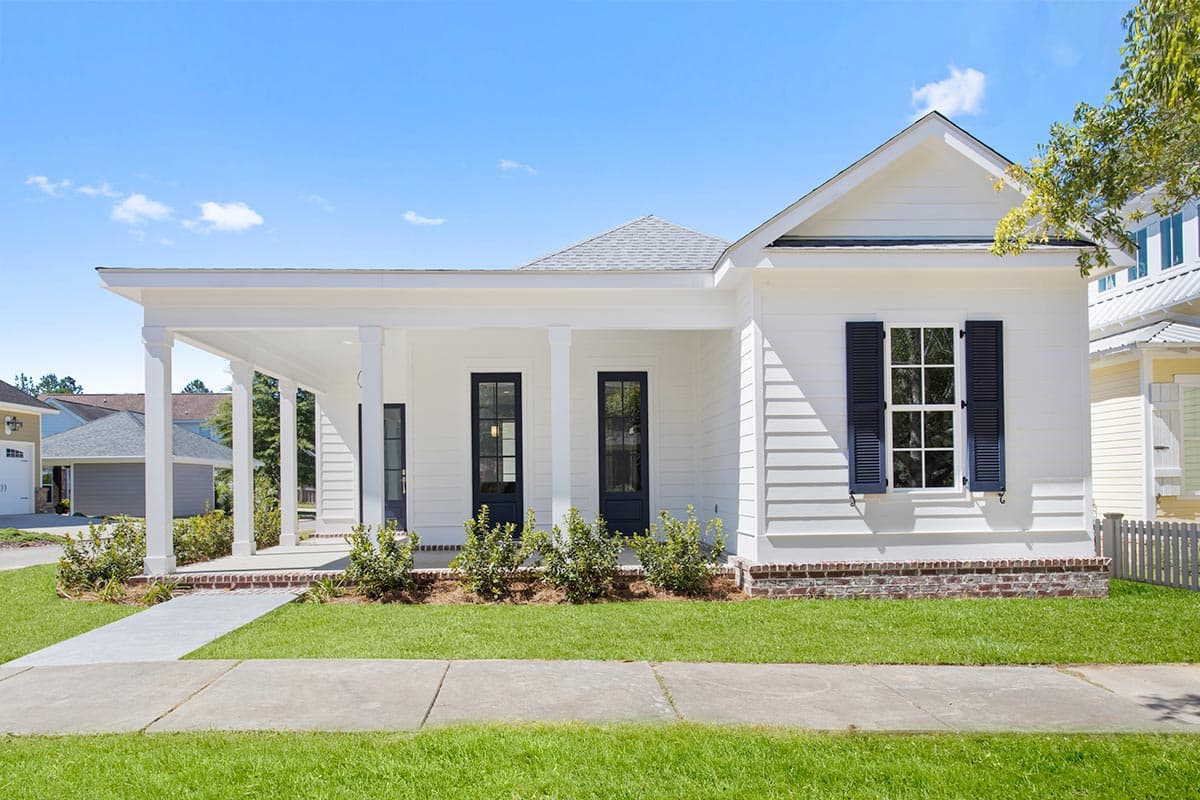 House plan exterior featuring a single-story design, front porch with columns, gabled roof, and symmetrical facade with shuttered windows.