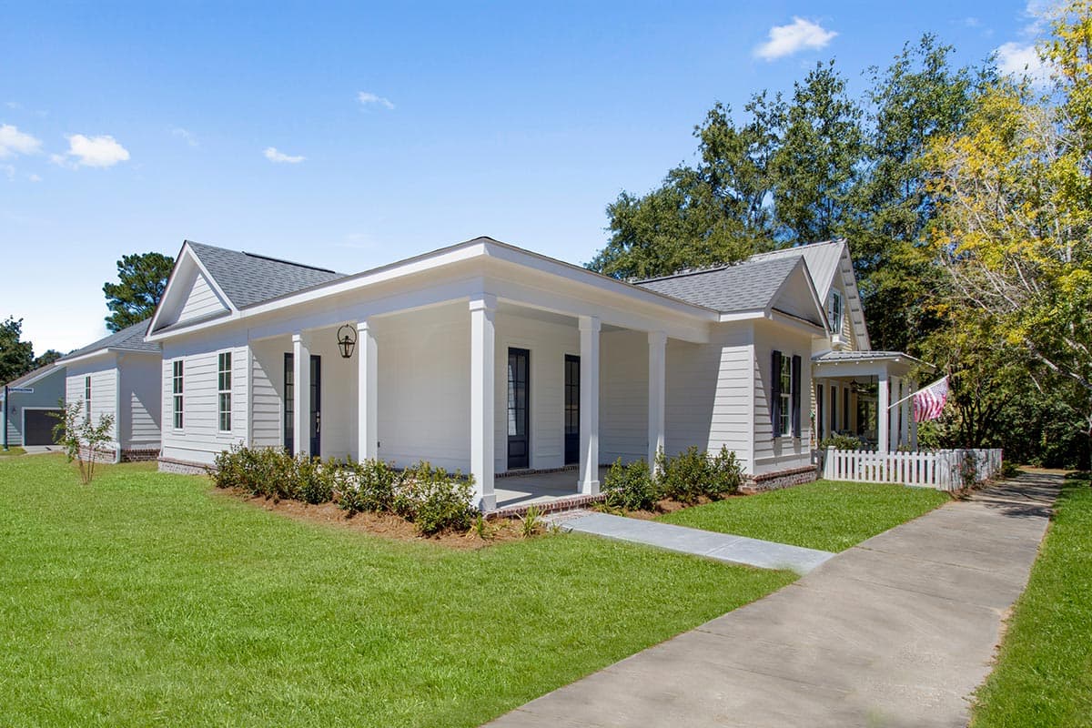 House plan exterior: White siding, one-story home with a covered front porch, gabled roof, and attached garage.
