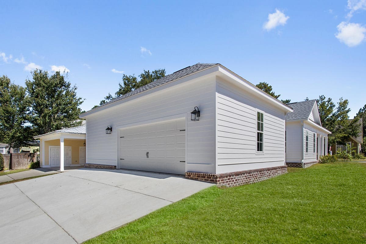 House plan exterior featuring a two-car garage, covered porte-cochère with double doors, and white horizontal siding.