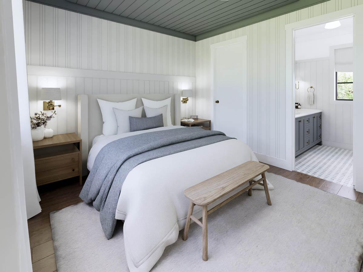A bright, modern bedroom featuring a white bed with a grey throw, a wooden bench, and a view into a bathroom with a grey vanity.