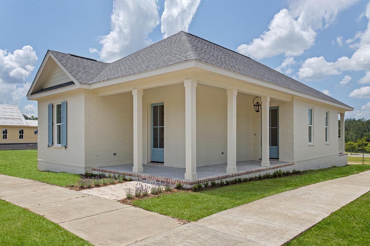House plan exterior: Single-story brick home with covered porch, gables, and blue shutters.