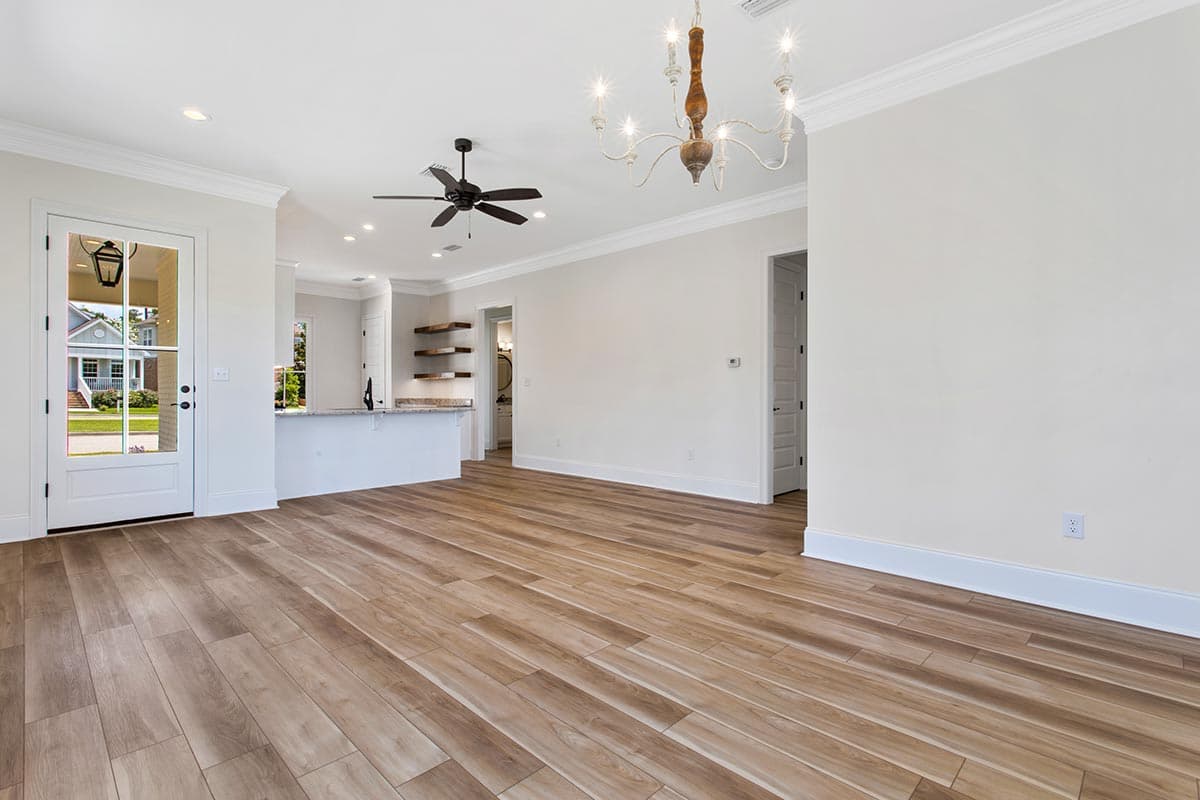 Interior view of open-concept living area with wood-look flooring, a kitchen island, and a glass-paneled door.