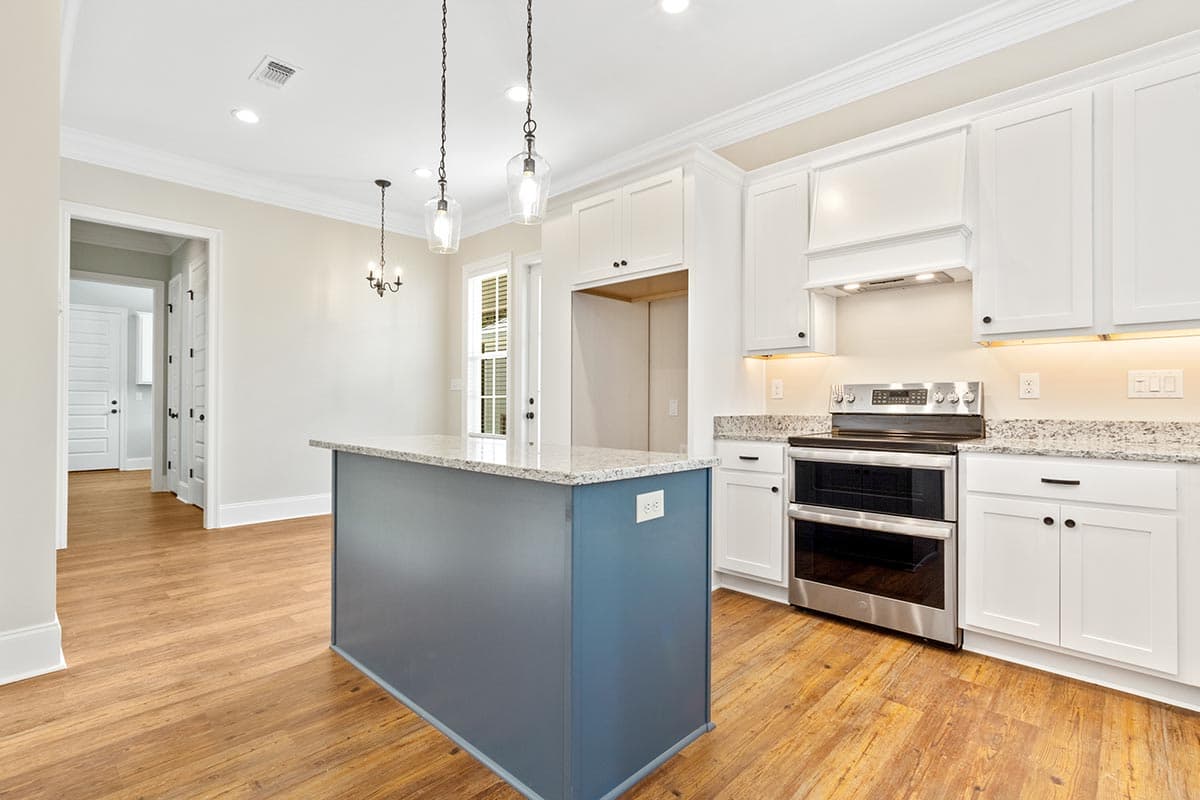 Kitchen with white cabinets, granite countertops, a blue island with pendant lights, stainless steel double oven, and wood plank flooring.