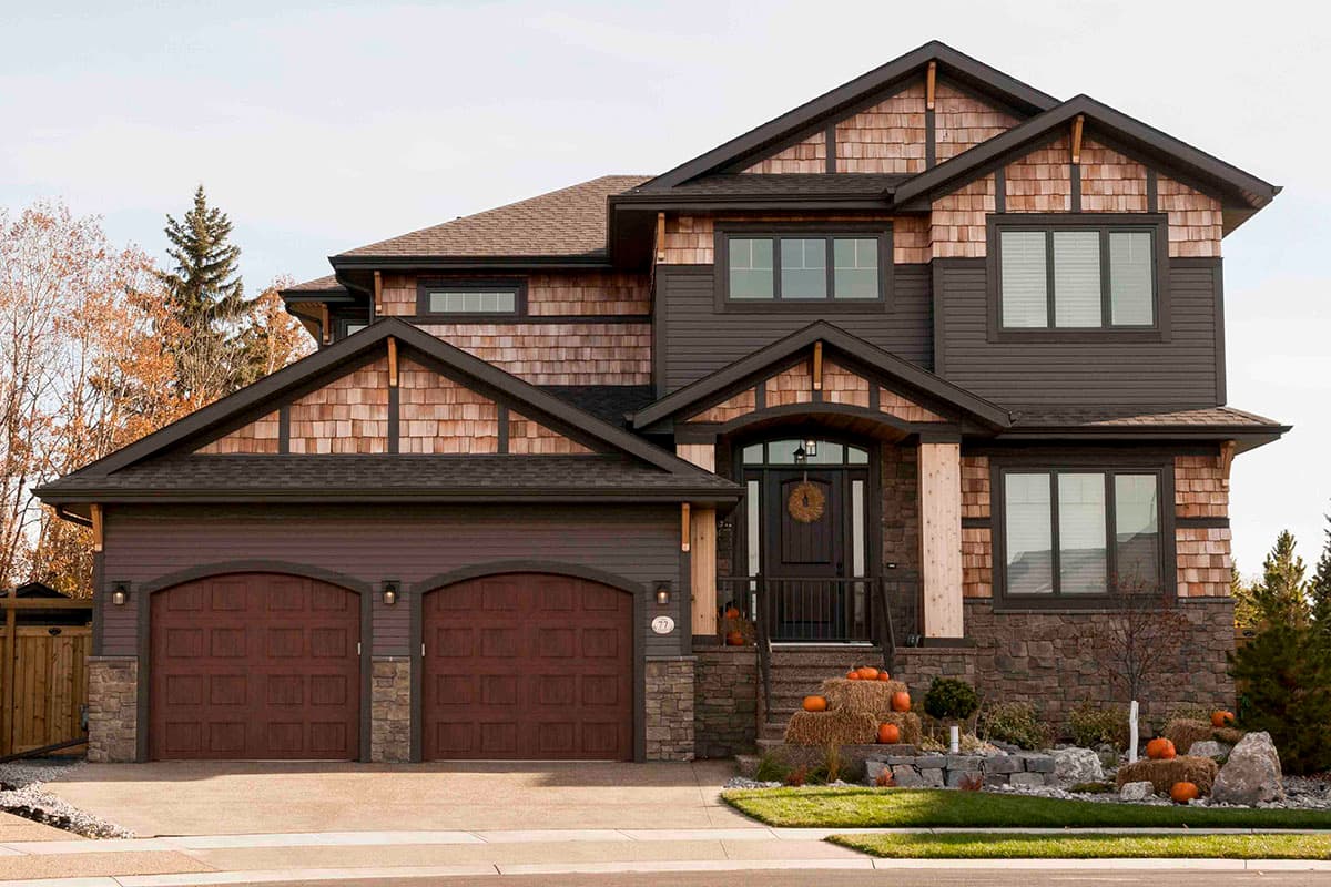 House plan exterior. Two-story Craftsman home with a gabled roof, shake siding, and a covered entry porch with stone accents.