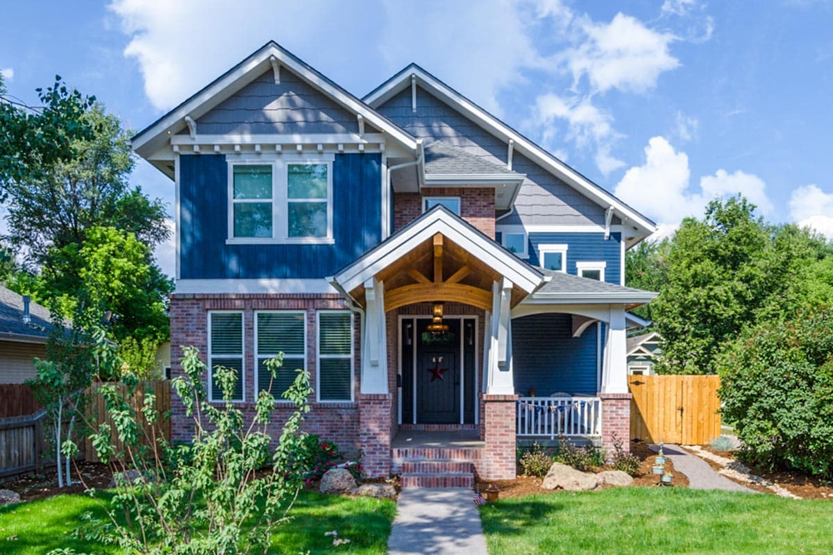 House plan exterior. Two-story Craftsman home with a front porch, gables, and a mix of brick and siding. Features a covered entry.