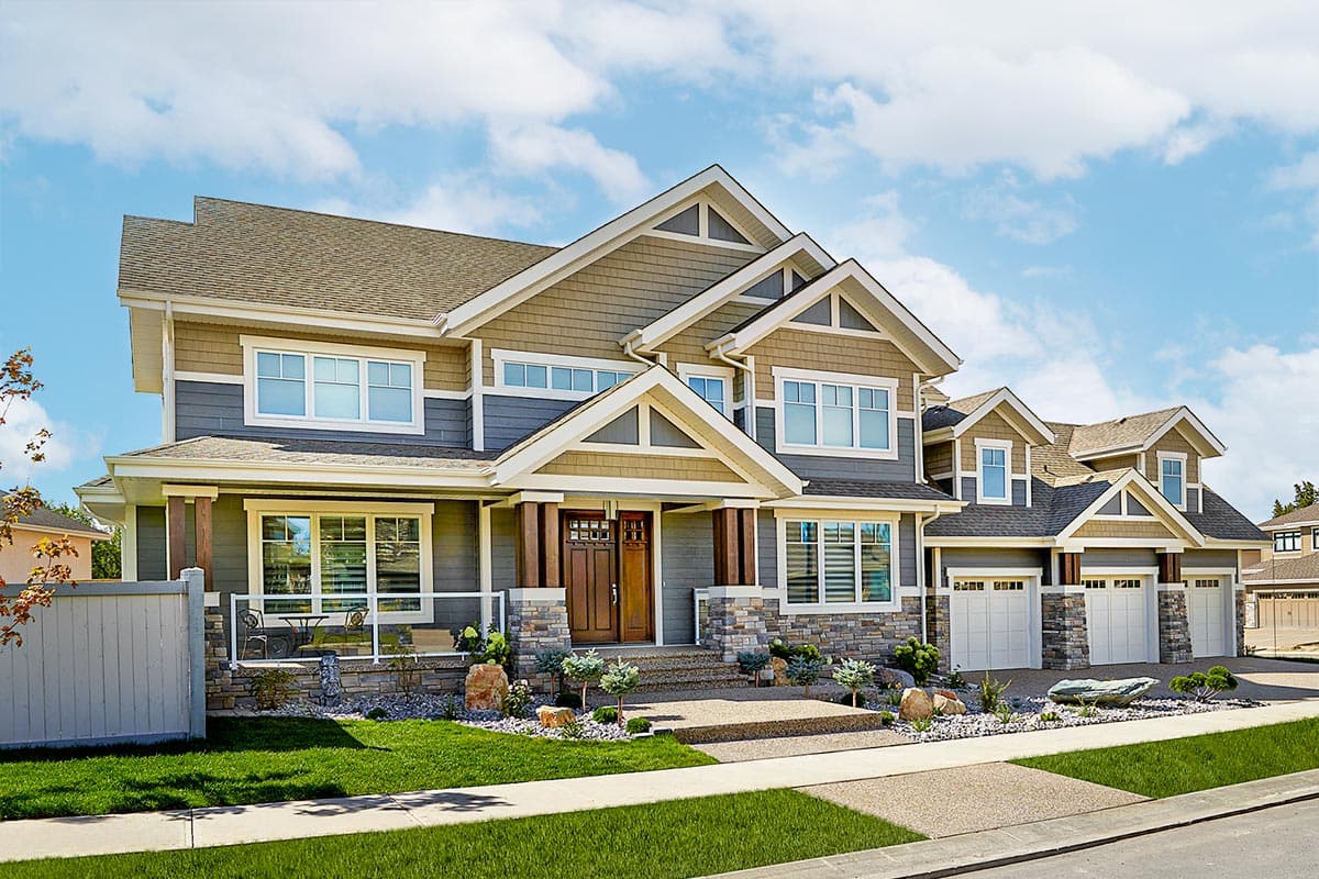 House plan exterior. Two-story Craftsman home with gabled roof, stone accents, front porch with columns, and a three-car garage.