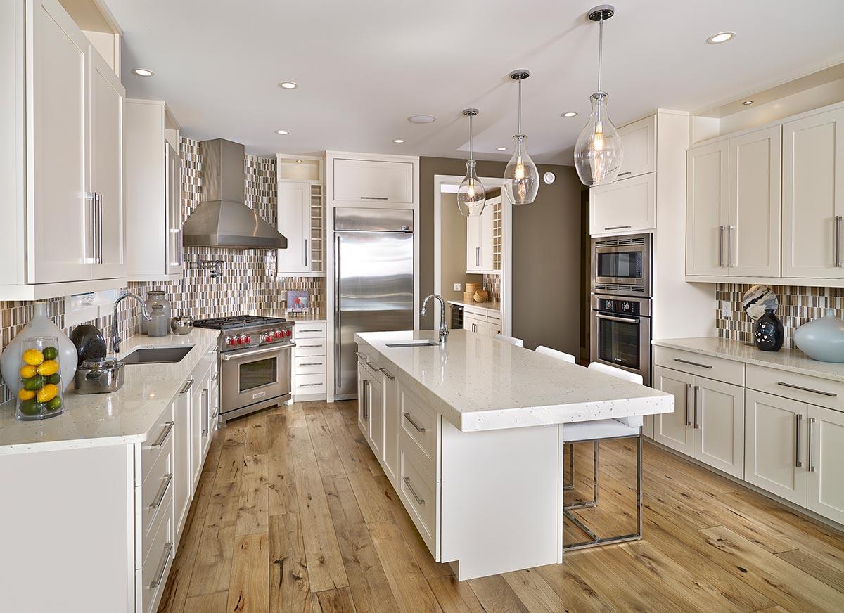 Kitchen with white cabinets, large island, stainless steel appliances, and tiled backsplash.