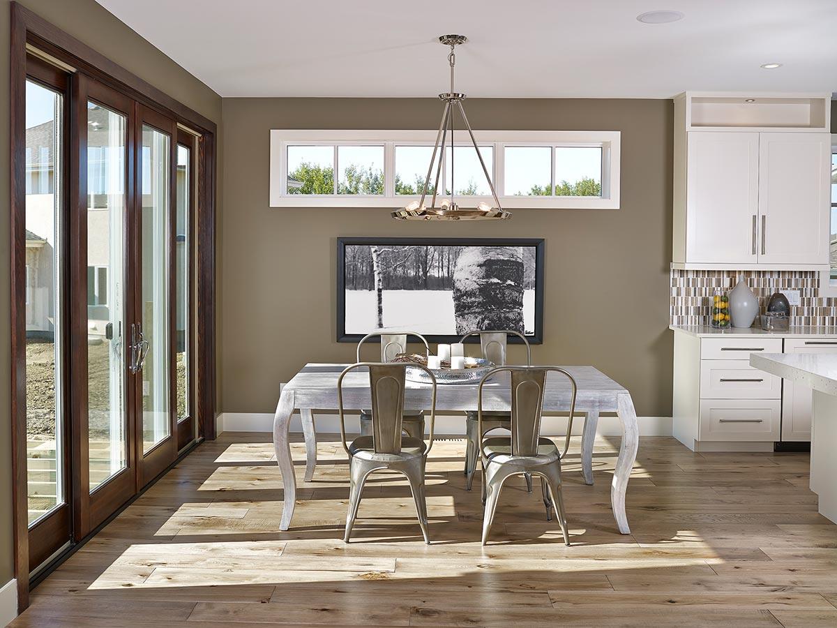 Dining area with wood sliding doors, a table with chairs, and white kitchen cabinets with a tiled backsplash.