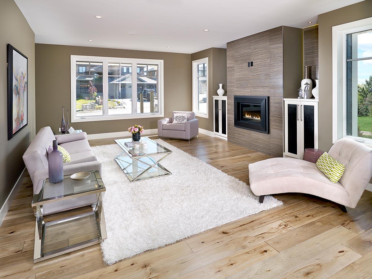 Living room with a large fireplace, sectional sofa, chaise lounge, glass coffee table, and wood floors.