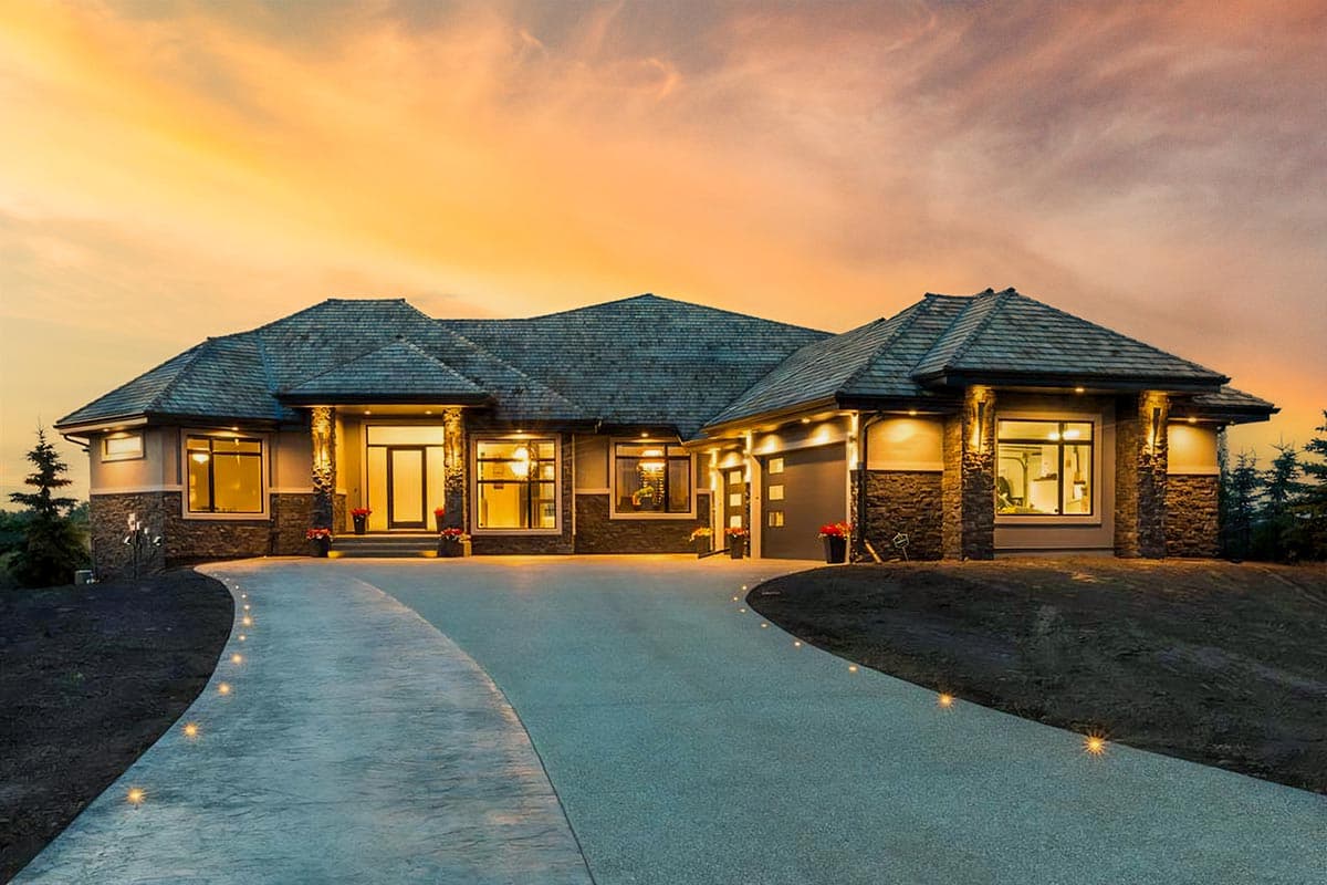 House plan exterior. Ranch-style home with multiple gabled rooflines, stone facade accents, and attached garage. Driveway leads to front entry.
