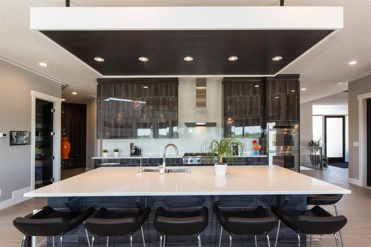 Modern kitchen with island, stainless steel appliances, contemporary cabinetry, and a tiered ceiling with recessed lighting.