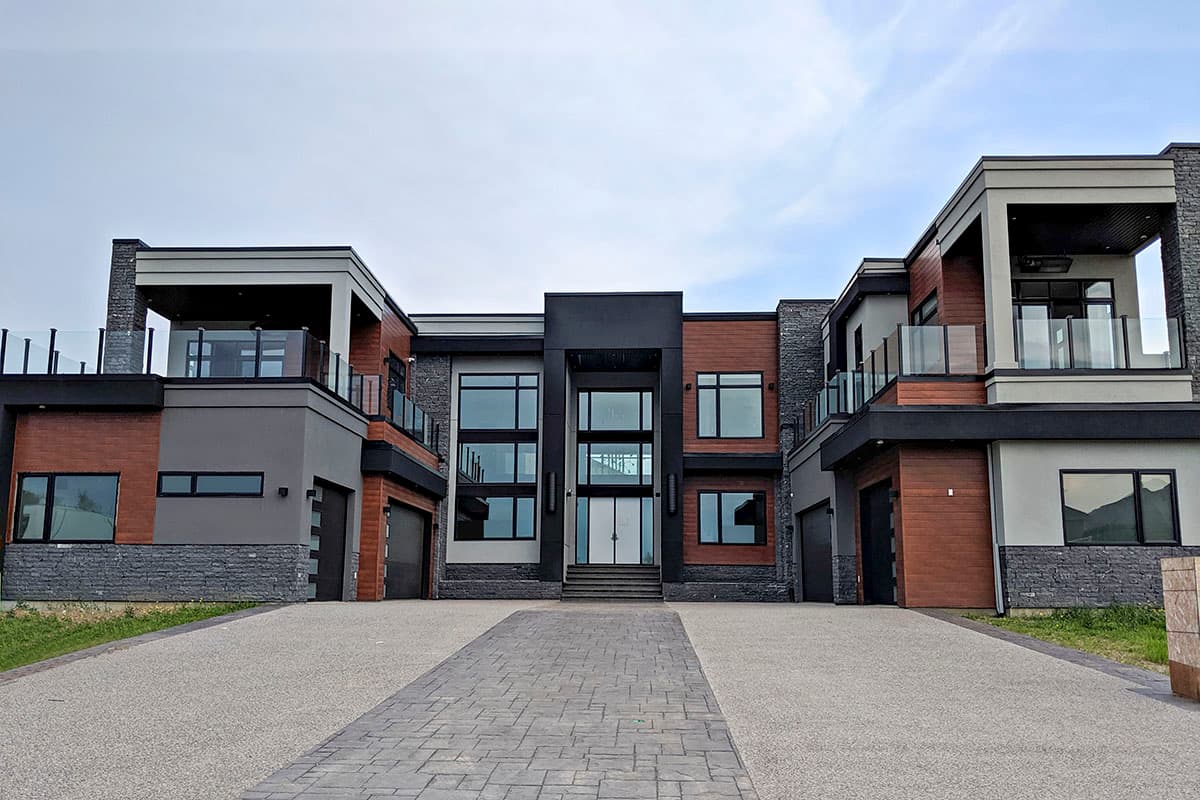 House plan exterior. Two-story modern home with flat rooflines, second-story balconies, and multiple large windows. Features wood and stone accents.