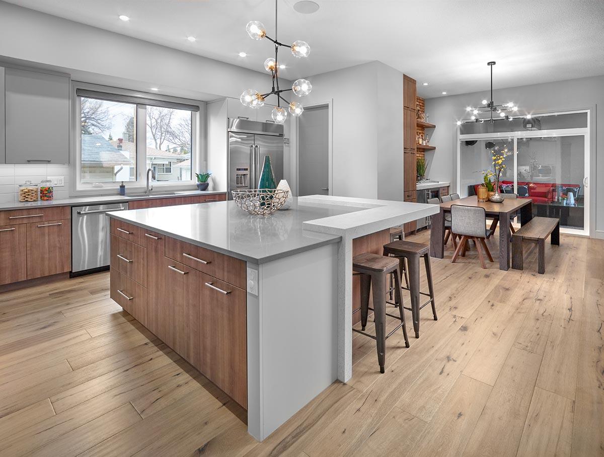 Modern kitchen with large island, dining area with sliding glass doors, and light wood floors.