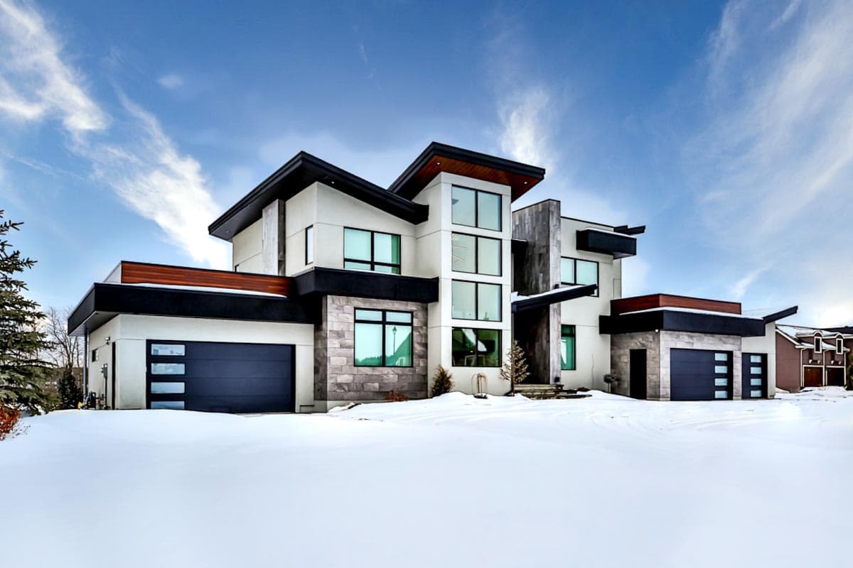 Modern two-story house plan exterior with multiple cantilevered sections, stone accents, and two integrated garages.