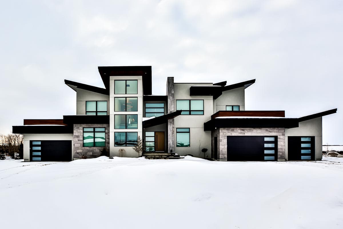 Modern house plan exterior with stacked stone accents, multiple garages, and cantilevered rooflines.