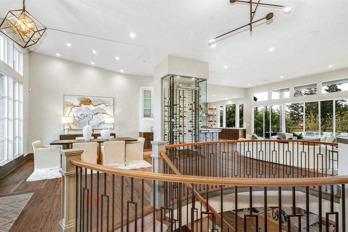 Interior view of open-concept living space with dining area, glass wine cellar, and great room with large windows.