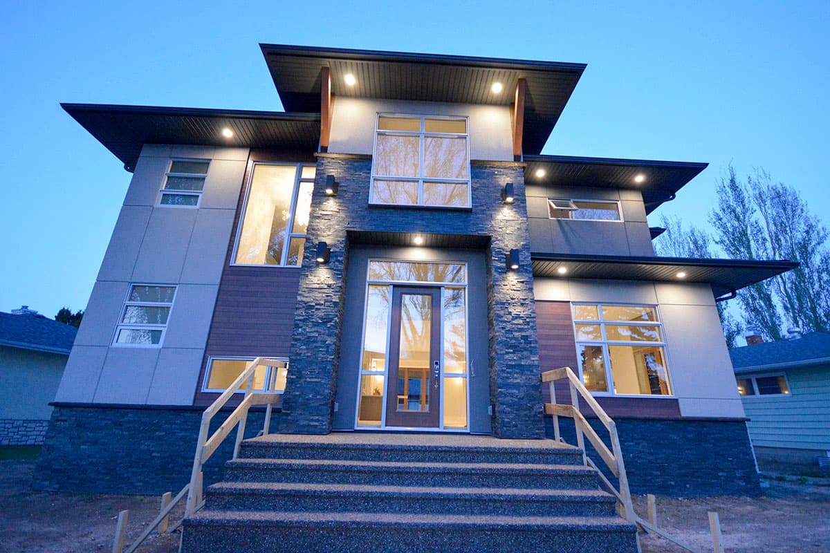 House plan exterior featuring a two-story modern design with flat rooflines, stone facade accent, and large windows. Front entrance with steps.