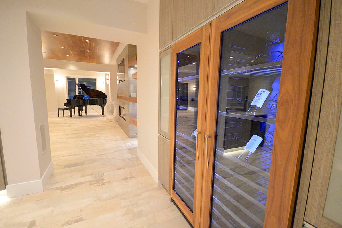 Interior view of a living space with a grand piano, fireplace, and a dual-zone wine cooler with wood cabinetry.