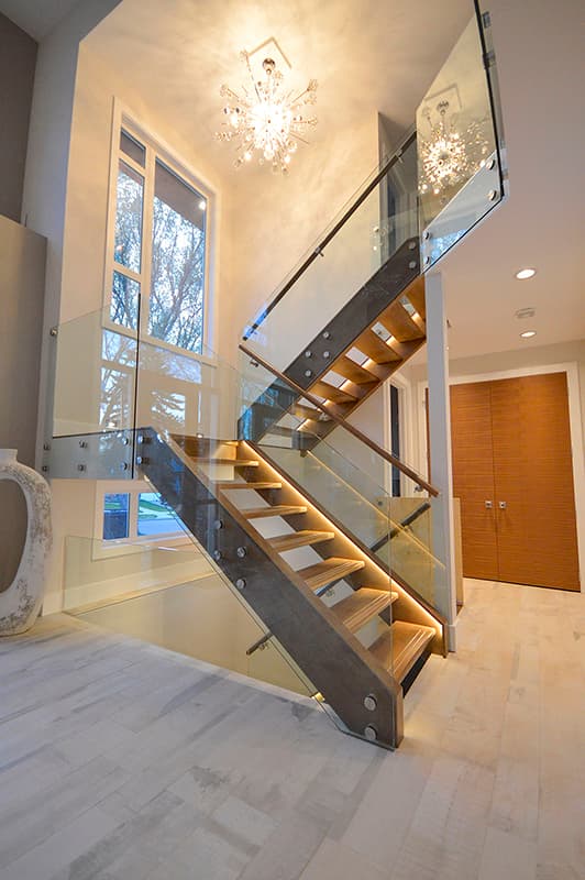 Modern staircase with wood treads, glass railings, and integrated LED lighting.