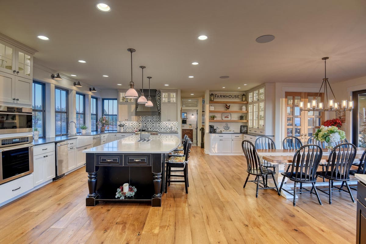 Open-concept kitchen and dining area with large island, farmhouse sink, and modern chandelier.