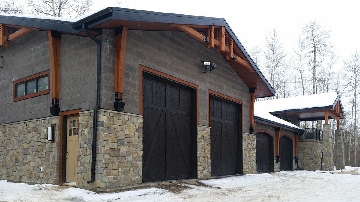 House plan exterior with stone foundation, wood beam accents, dark garage doors, and covered patio.