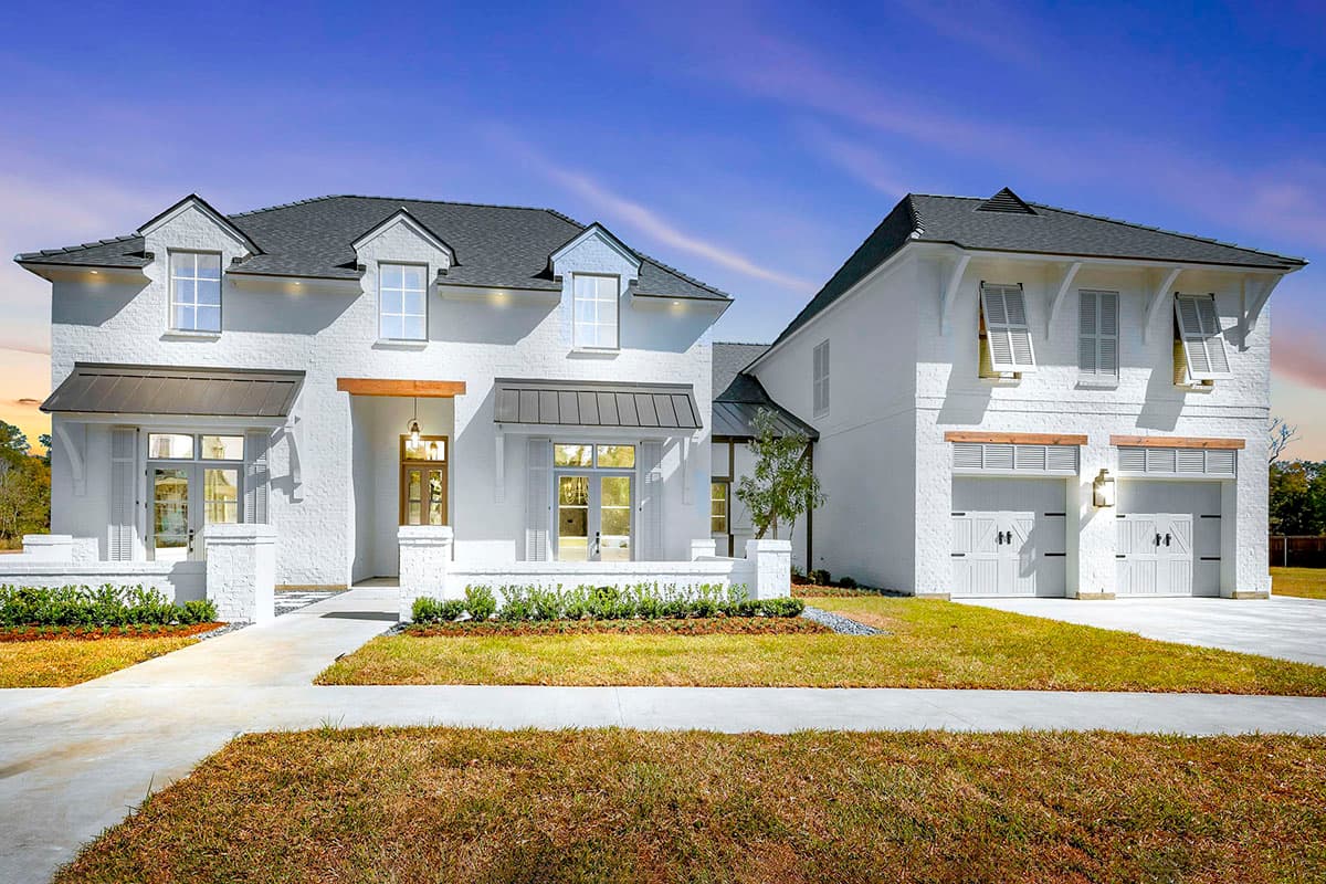 House plan exterior with two stories, gabled rooflines, dormers, and a detached garage. Features shutters and a covered porch.