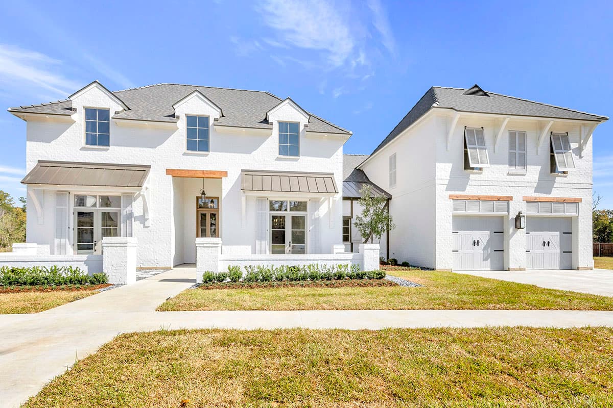 House plan exterior. Two-story, white brick, modern farmhouse style with dormers, awnings, and attached garage. Includes shutters and wood accents.