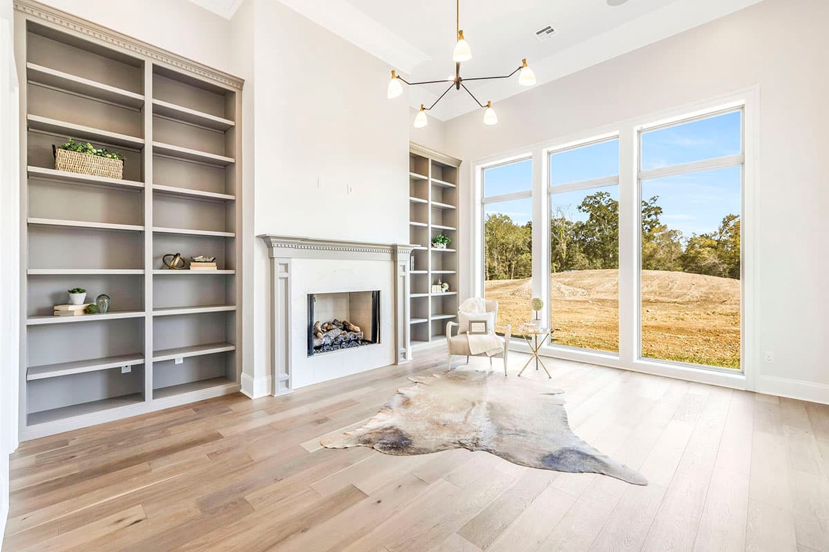 Great room rendering with fireplace, built-in bookshelves, and large windows offering an expansive outdoor view.