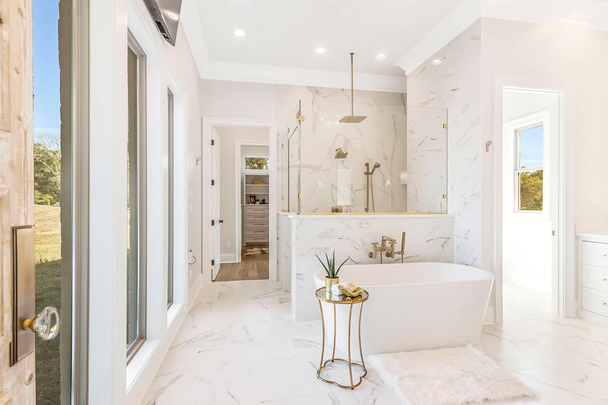 House plan bathroom interior with freestanding tub, walk-in shower, large windows, and marble tile flooring.