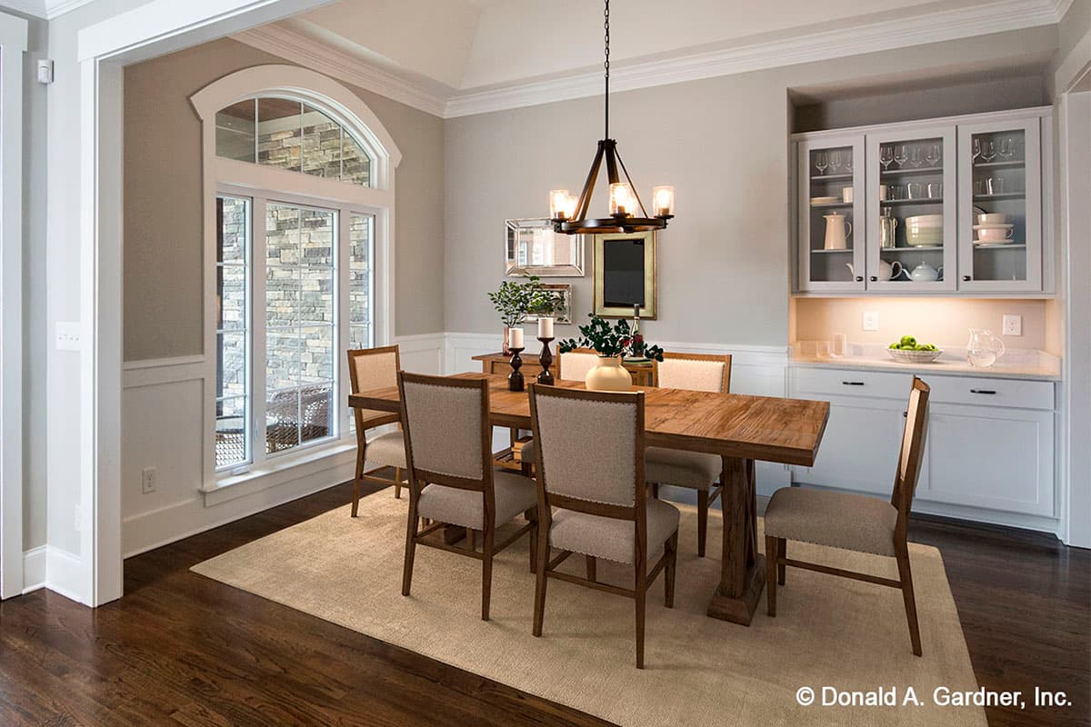 Dining room with wood table and chairs, arched window, and built-in buffet cabinetry.