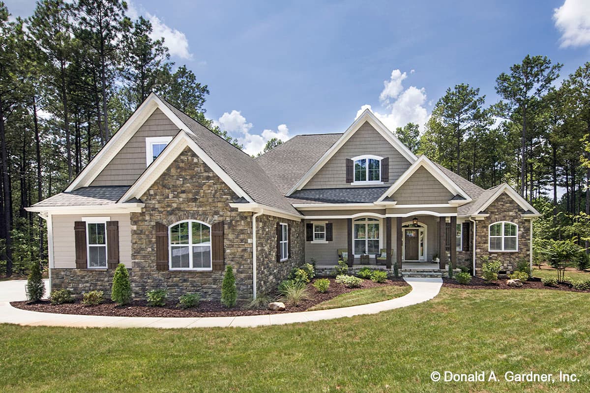 House plan exterior. One-story Craftsman with stone and shingle siding. Features include multiple gables, arched windows, and a covered porch.