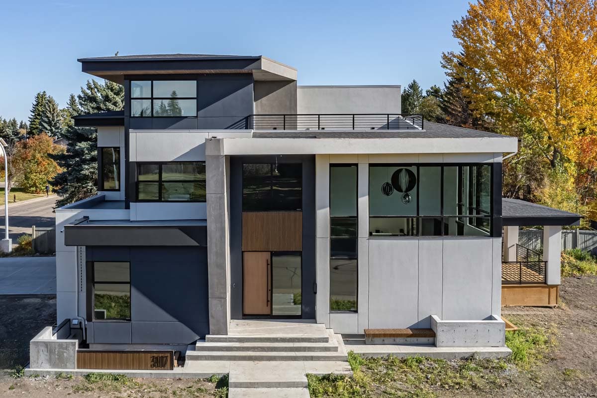 House plan exterior. Modern style, two-story home with flat rooflines, large windows, and a concrete entrance with bench.