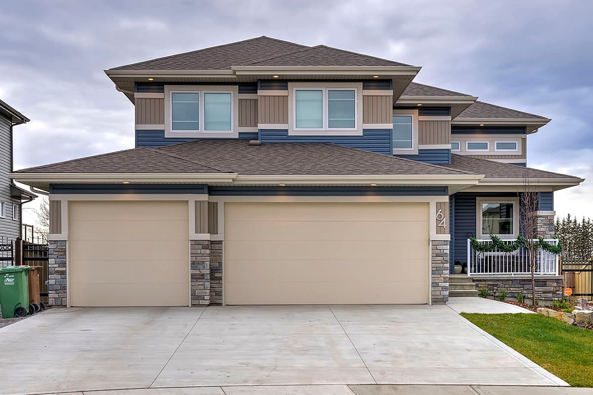 House plan exterior with two-story design. Features include a two-car garage, multiple gables, stone accents, and a covered porch. Dark roofline.