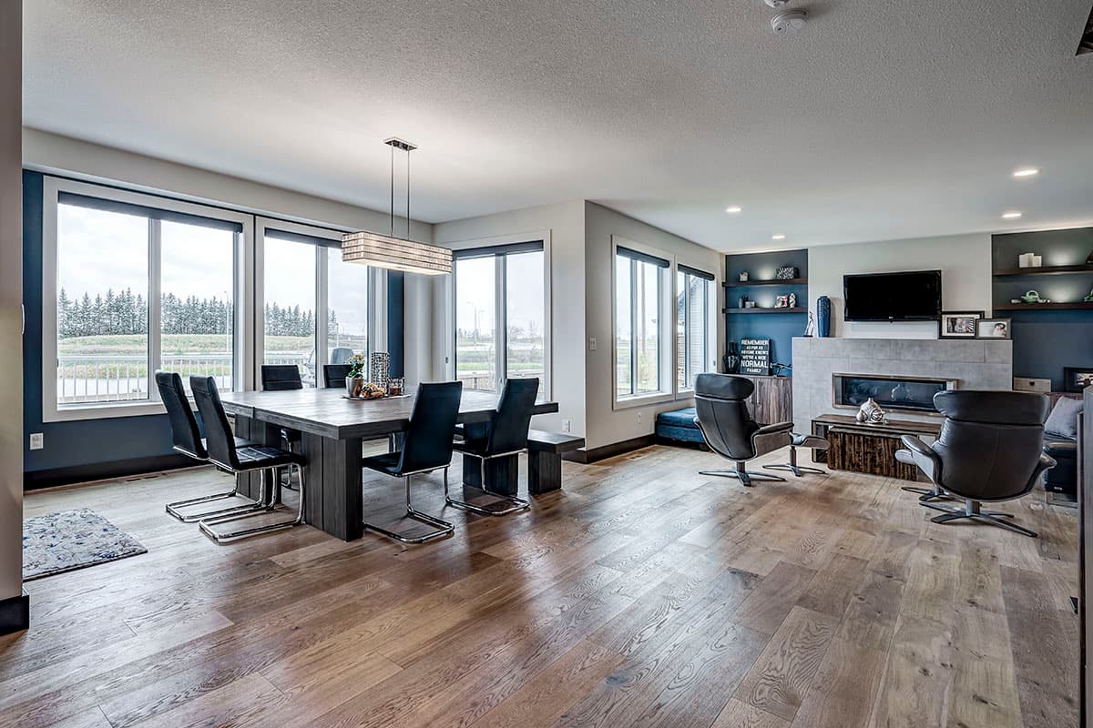 Open concept living and dining area with fireplace, large windows, and modern furniture.